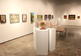 A gallery with sculptures on pedestals and paintings on the walls around them.